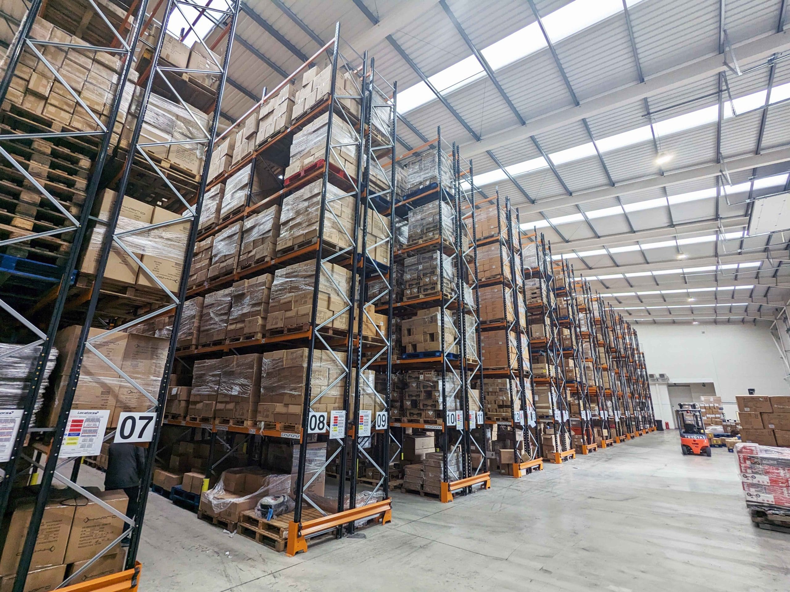 Pallet racking with barriers and rack protection. In the distance on the right-hand side is a Toyota forklift.